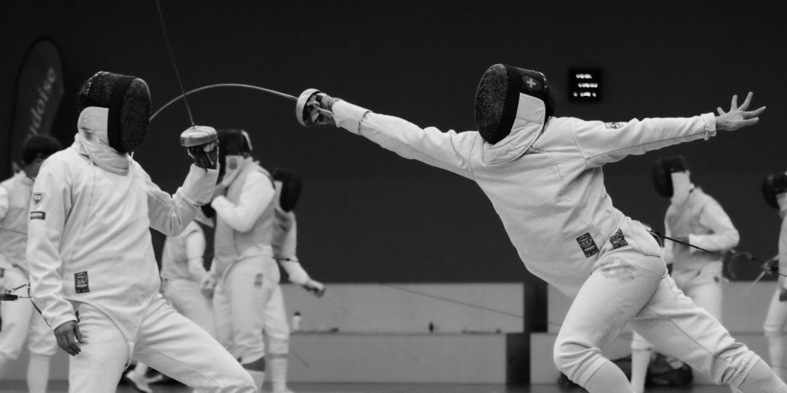 a group of people on a court with fencing equipment