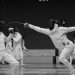 a group of people on a court with fencing equipment