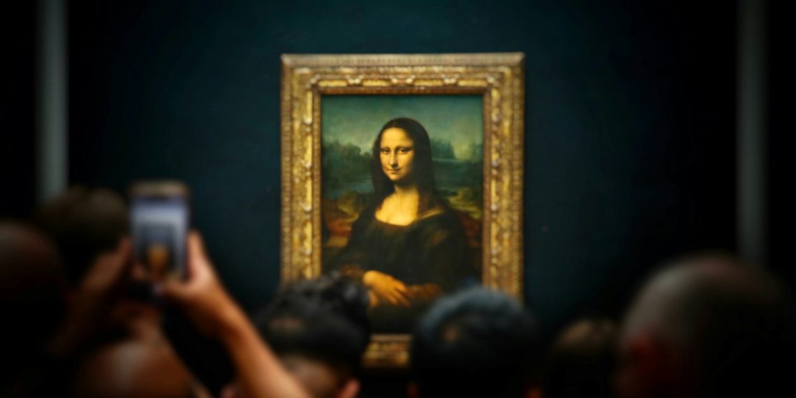 A group of people taking pictures of a painting