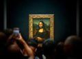 A group of people taking pictures of a painting
