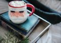 white and red ceramic mug on books