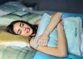 A woman sleeping peacefully in bed hugging a soft pillow, evoking comfort and relaxation.